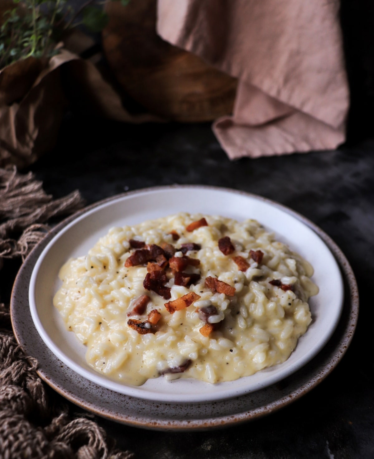 Top view of Roman-inspired risotto carbonara with golden guanciale pieces on a rustic plate.