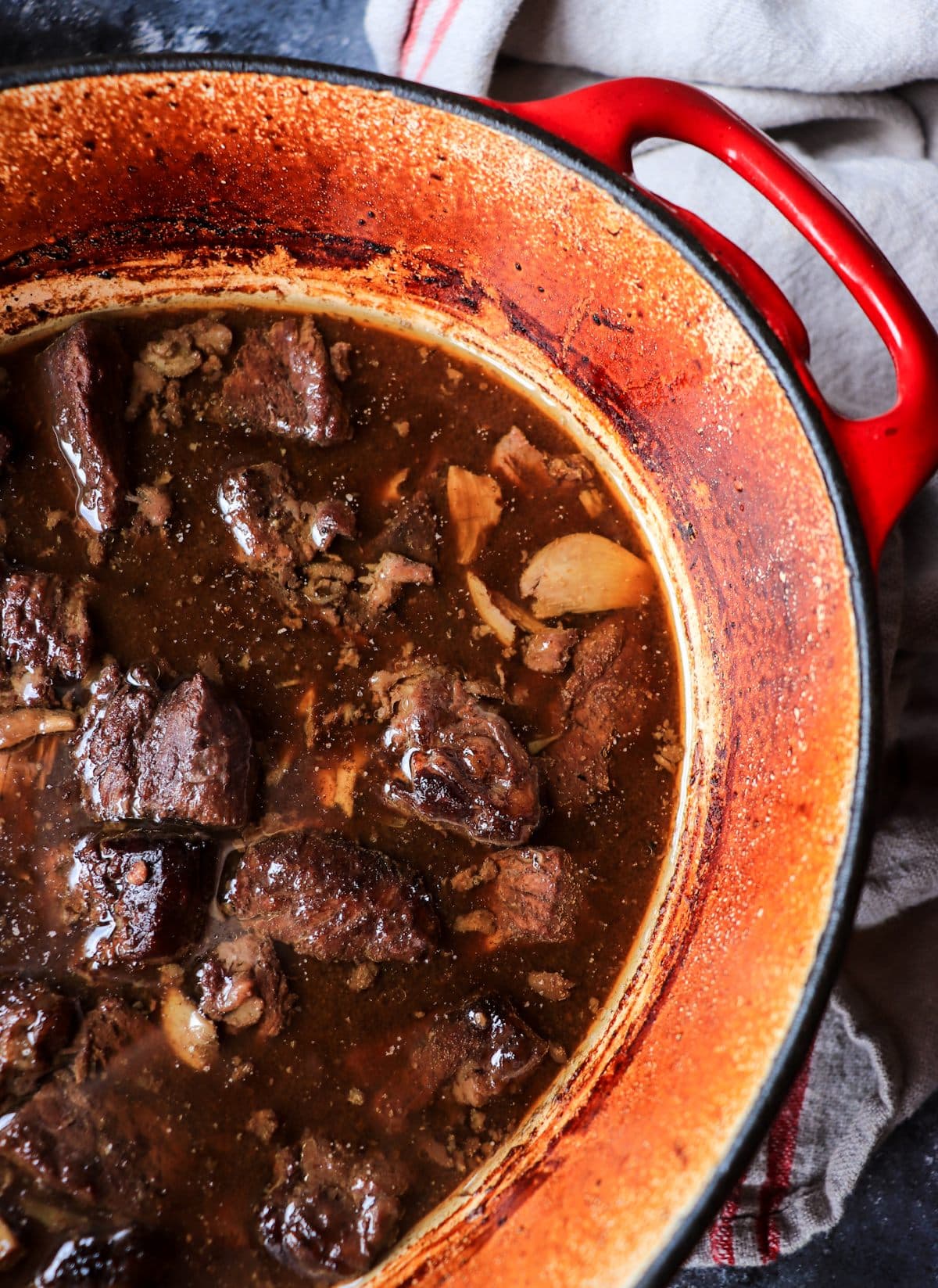 Peposo simmering in a red Dutch oven, with beef slowly braising in a dark red wine and black pepper sauce.