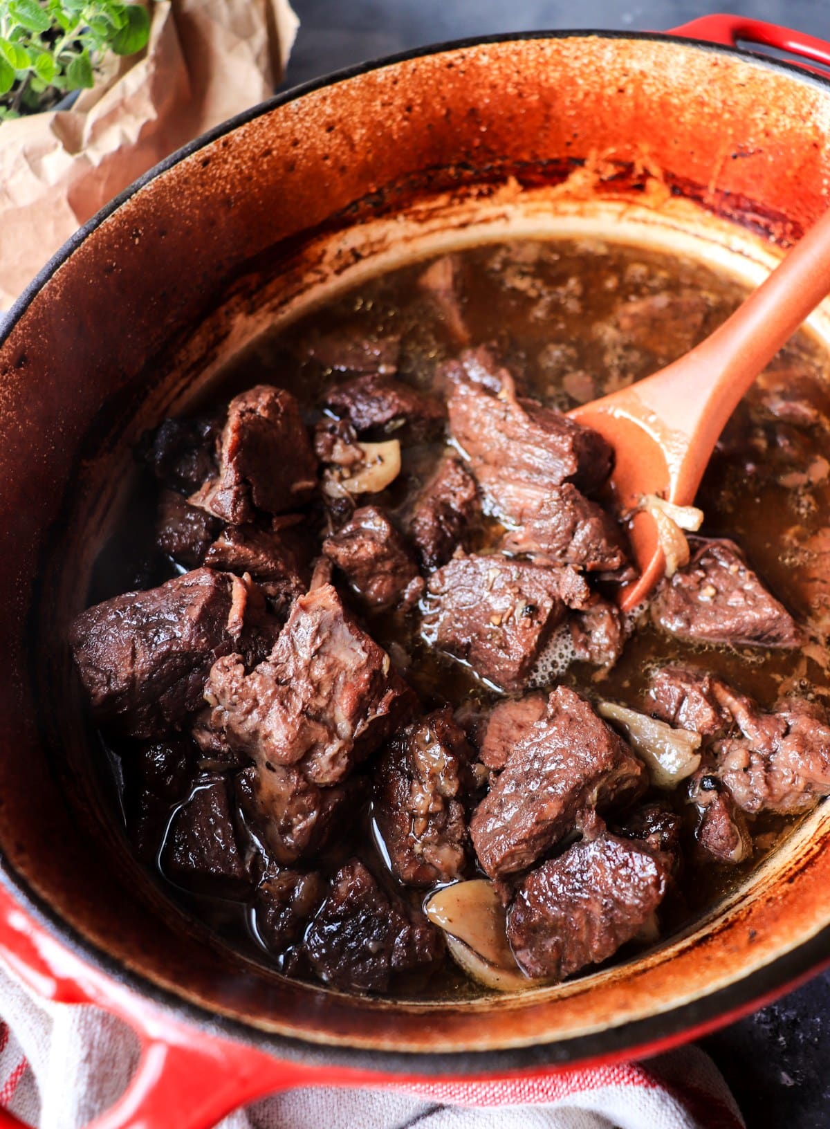 Peposo simmering in a red Dutch oven, with beef slowly braising in a dark red wine and black pepper sauce.