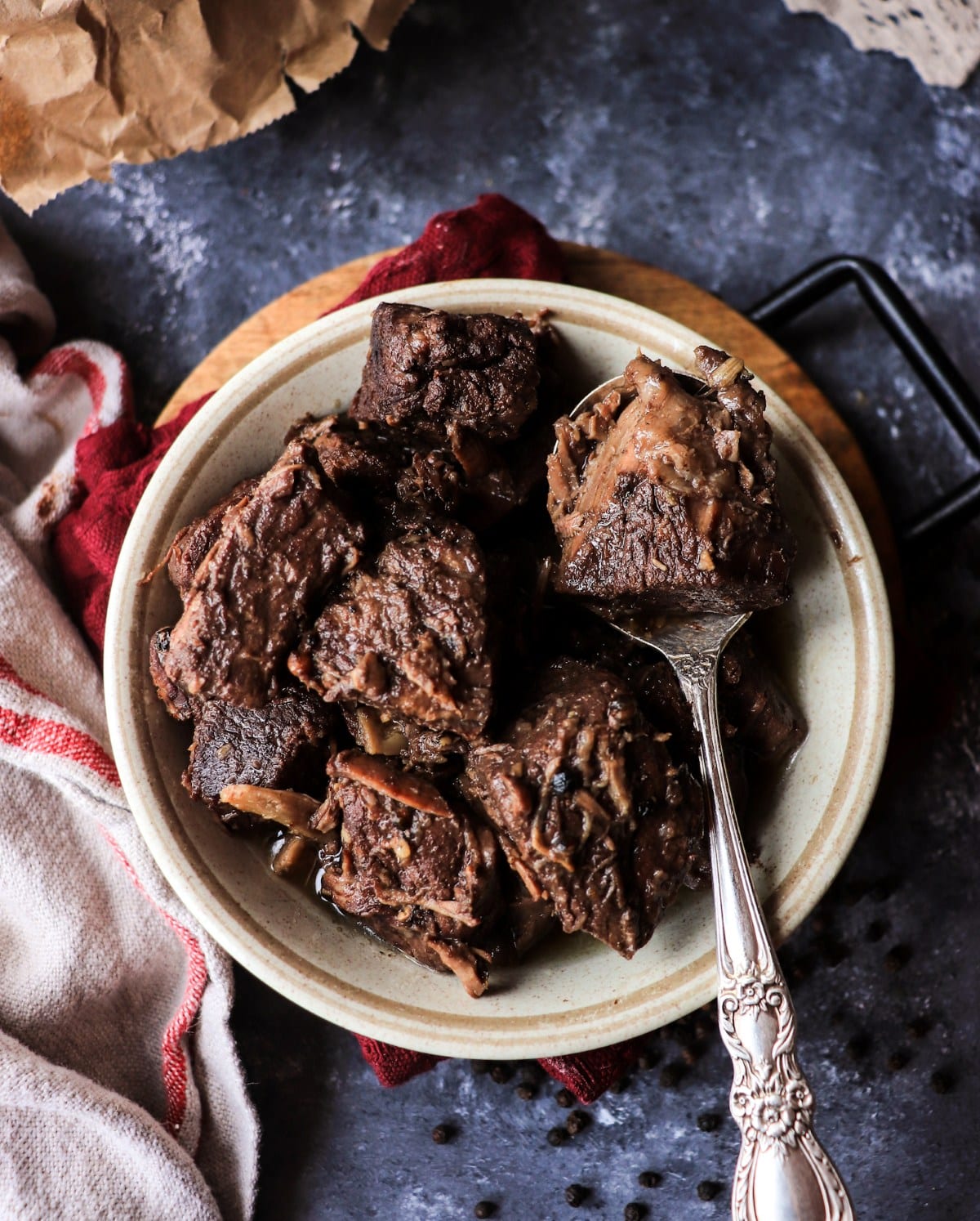 Overhead view of Tuscan Pepper Beef Stew in a ceramic bowl, showing tender beef chunks coated in rich wine sauce.
