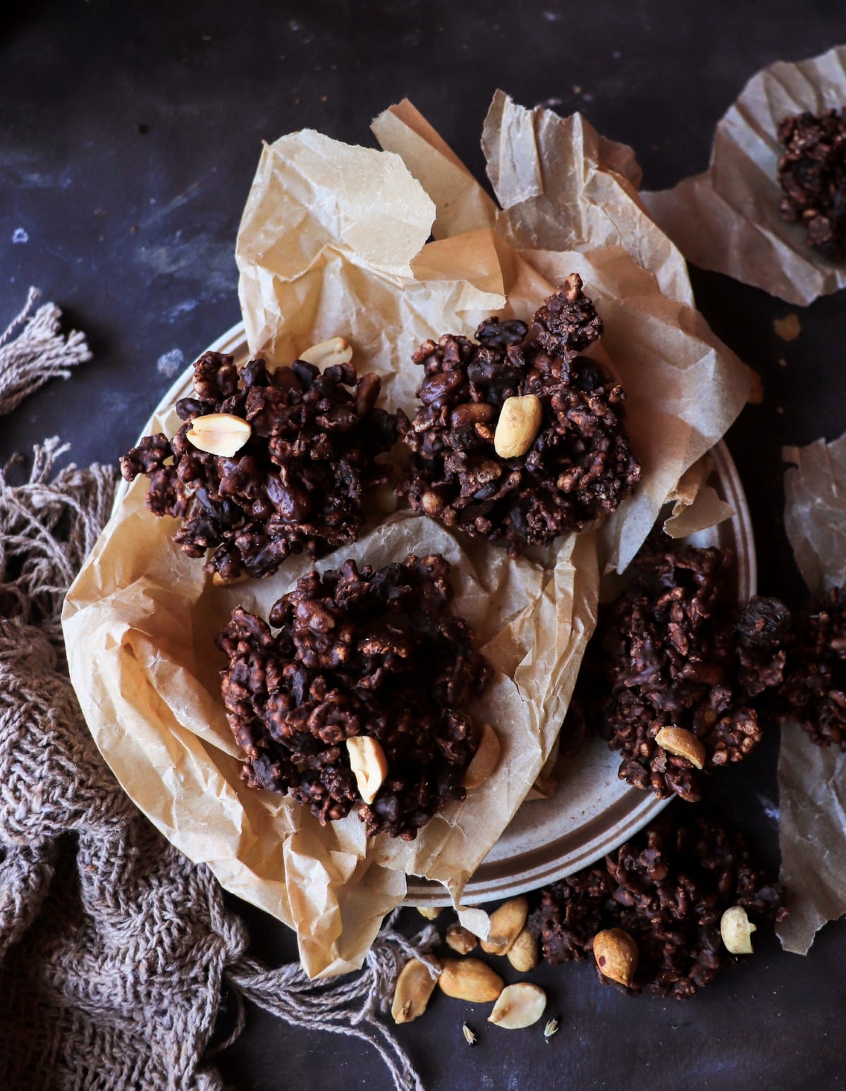 Espresso chocolate cornflake clusters with pine nuts and raisins on parchment paper, rustic no-bake dark chocolate cookies.