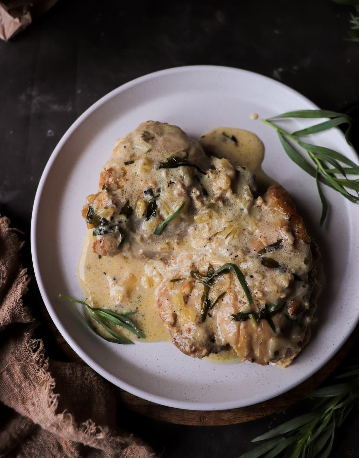 Creamy tarragon chicken with shallots and white wine sauce, close-up plated view.