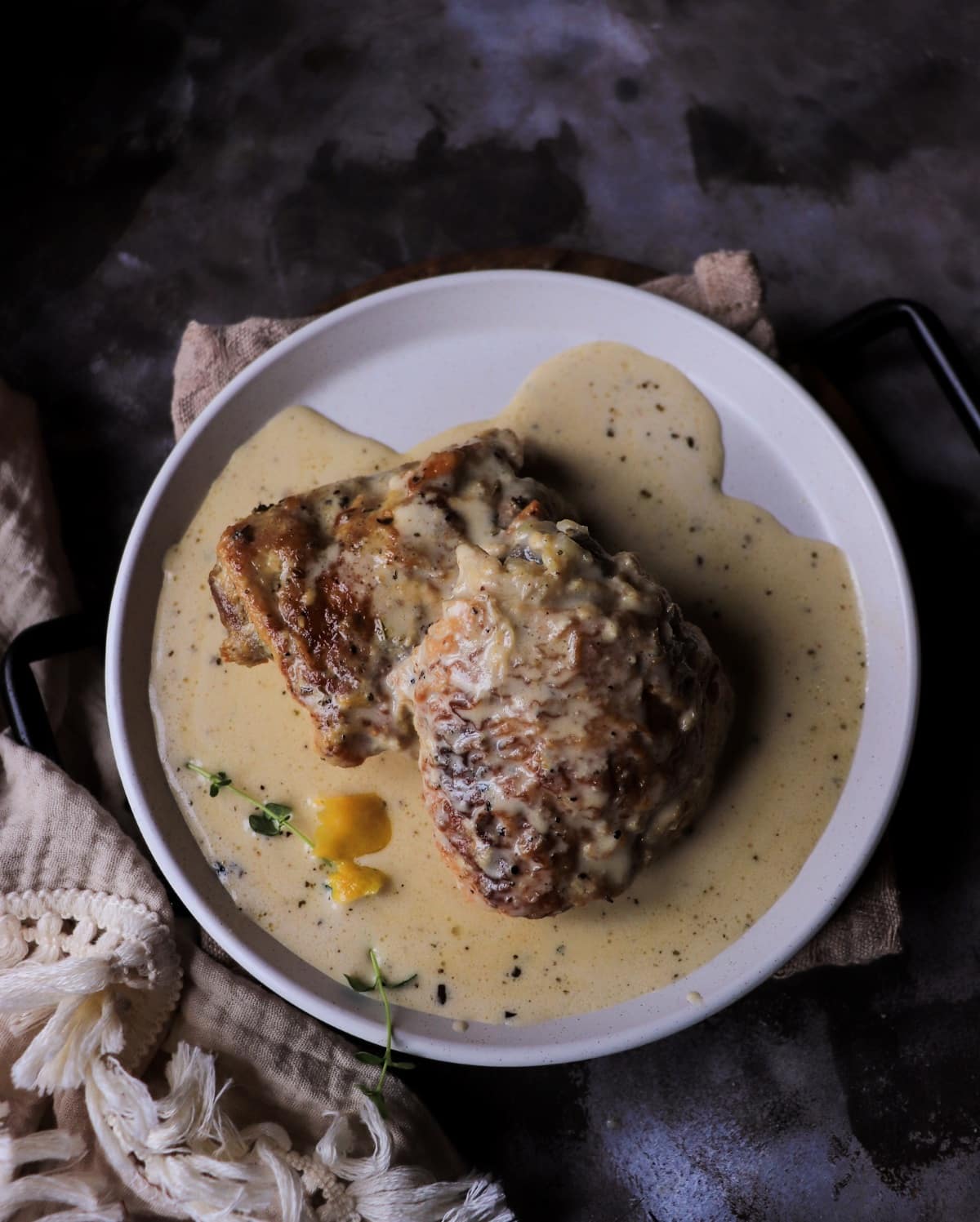Italian chicken in milk plated with creamy sauce and visible pepper and herbs.