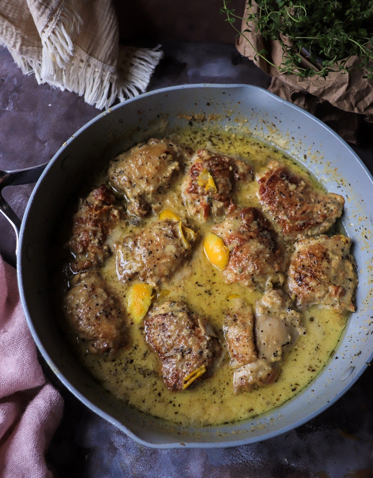 Chicken in milk simmering in a pan with lemon peel and curdled milk sauce during cooking.