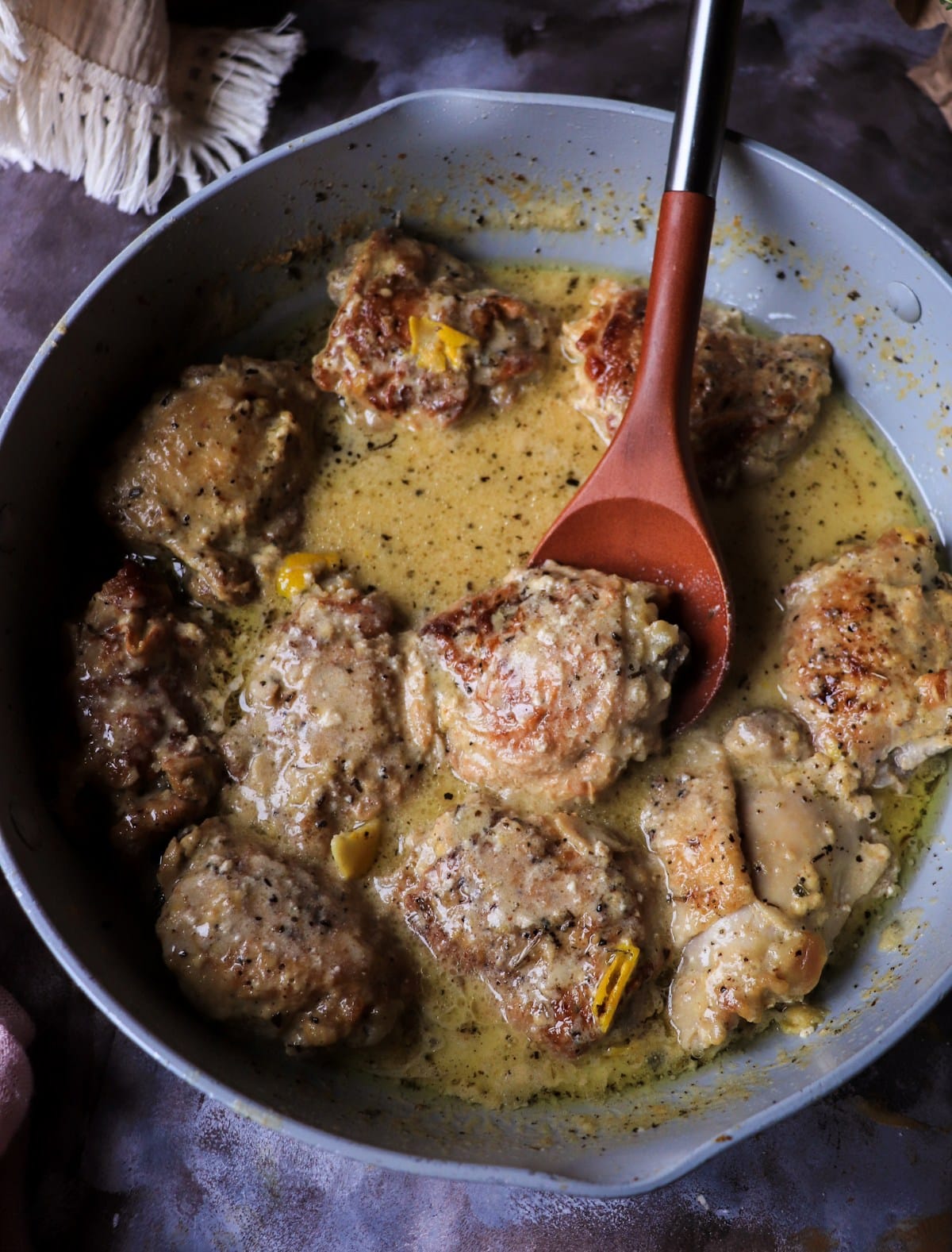 Milk braised chicken with soft curds and rich sauce stirred in a skillet.