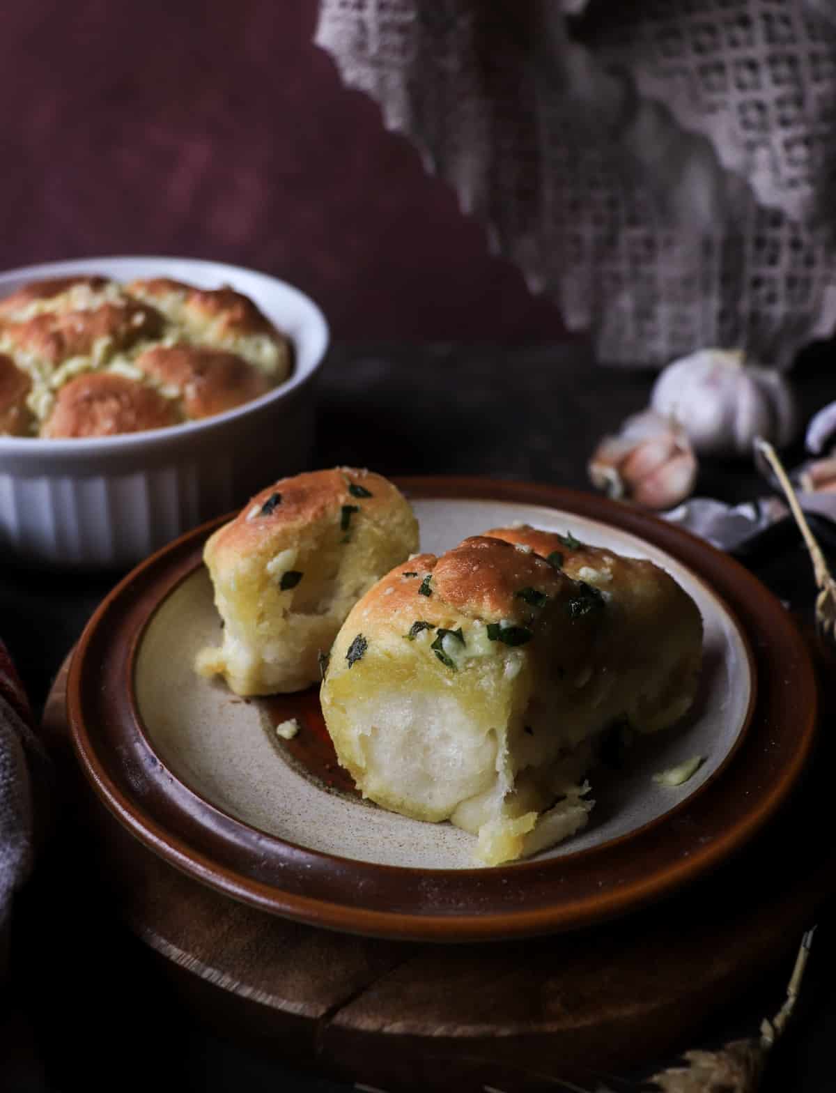 Fluffy pull-apart Pampushky served warm on a plate, with more buns in the background.