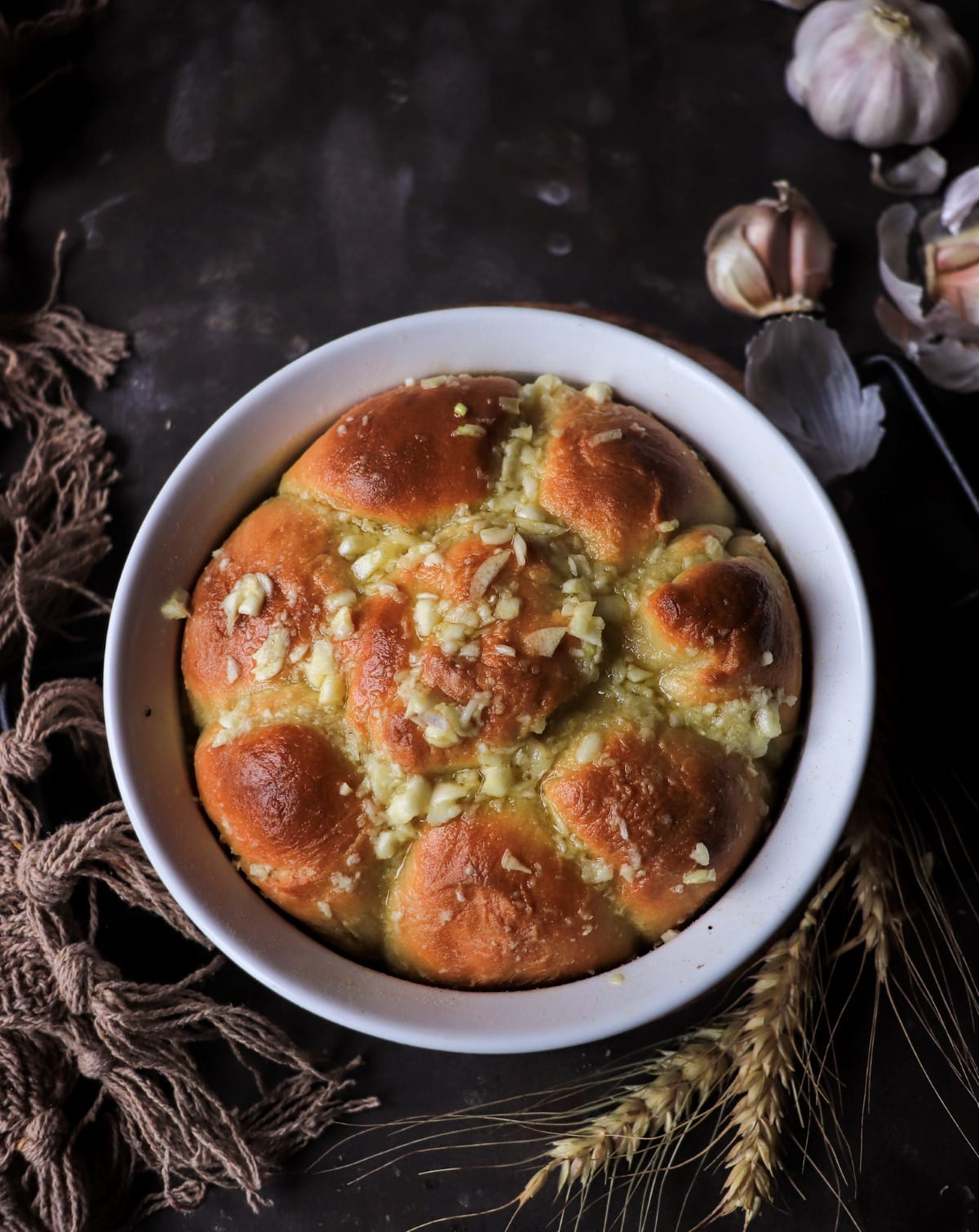 Freshly baked Pampushky brushed with garlic and olive oil in a white baking dish.