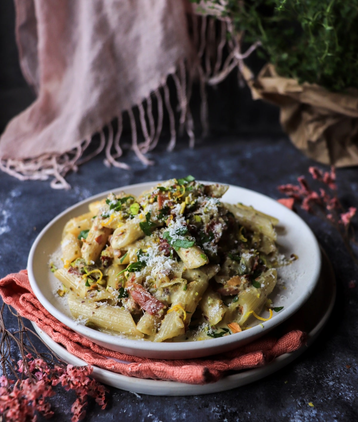Italian pistachio cream pasta with speck, parmesan, lemon zest, and fresh herbs on a plate