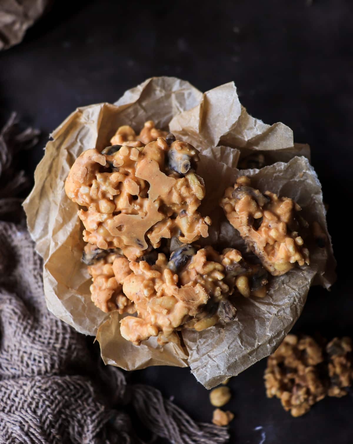 Peanut butter haystacks style cornflake peanut raisin clusters on parchment paper