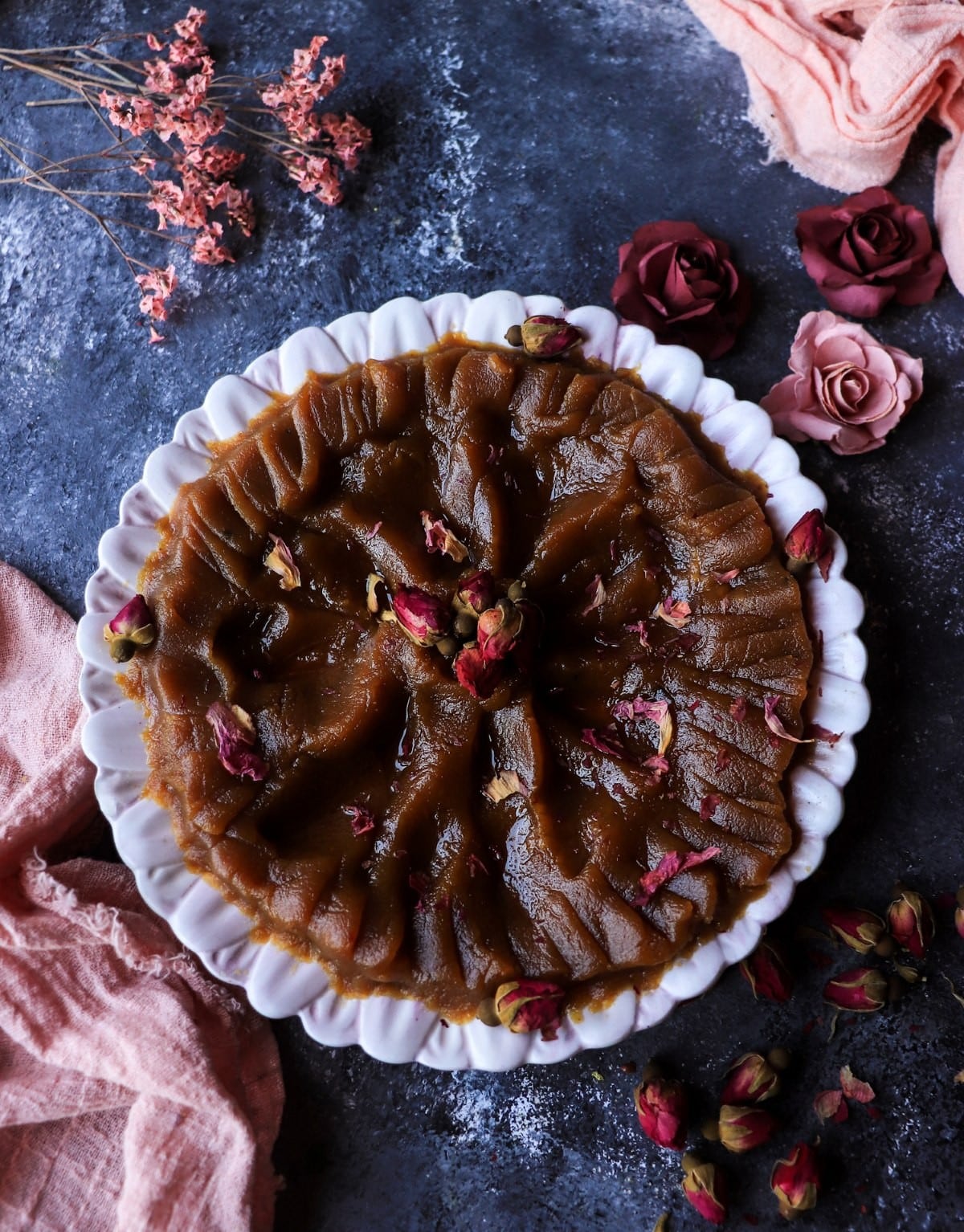 Persian saffron halva with rosewater and cardamom on a plate, decorated with dried rose petals