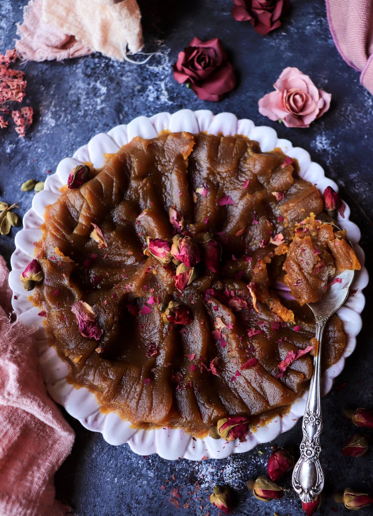 spoon lifting Persian saffron halva with rosewater and cardamom, showing moist and tender texture