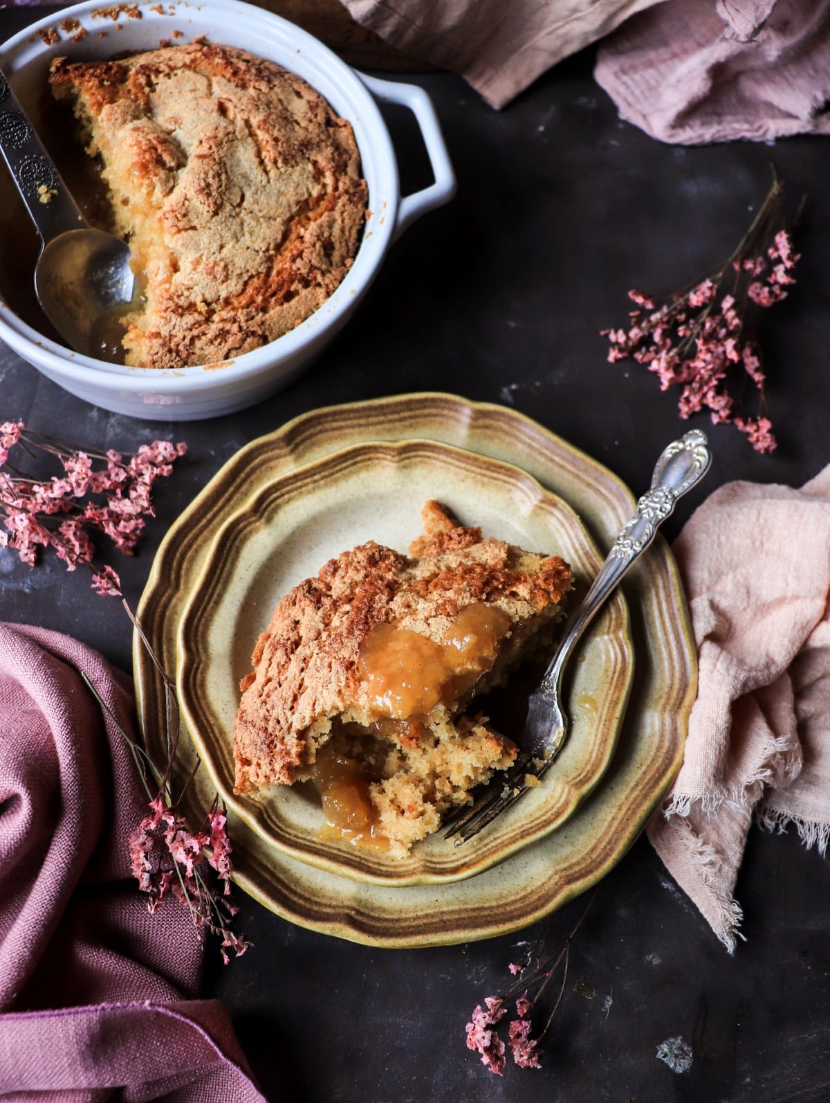 Classic maple syrup pudding cake plated with caramel-like sauce and baking dish in the background