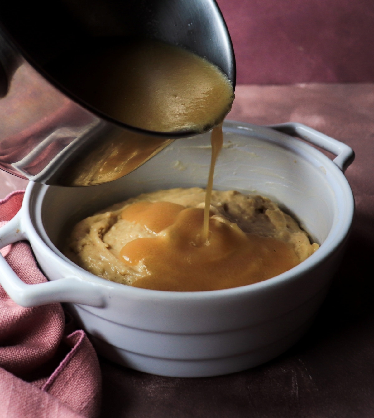 Hot maple syrup sauce being poured over batter for pouding chômeur before baking