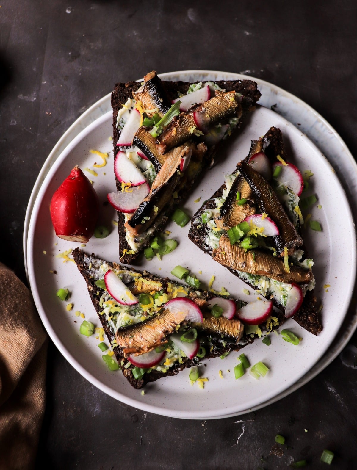 Buttered rye with smoked sprats, lemon butter, radishes, and green onions