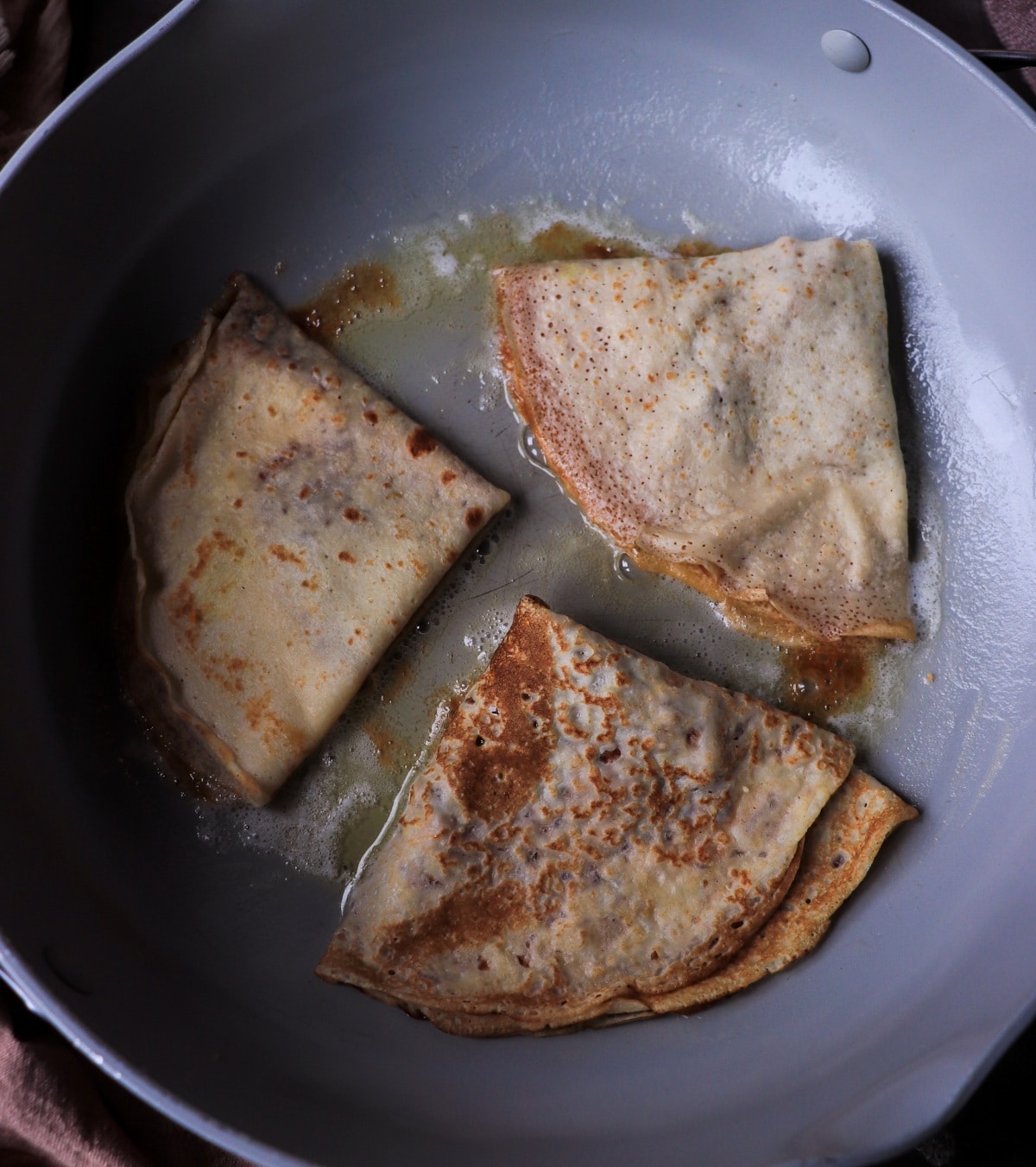 dulce de leche crepes frying in butter in a skillet