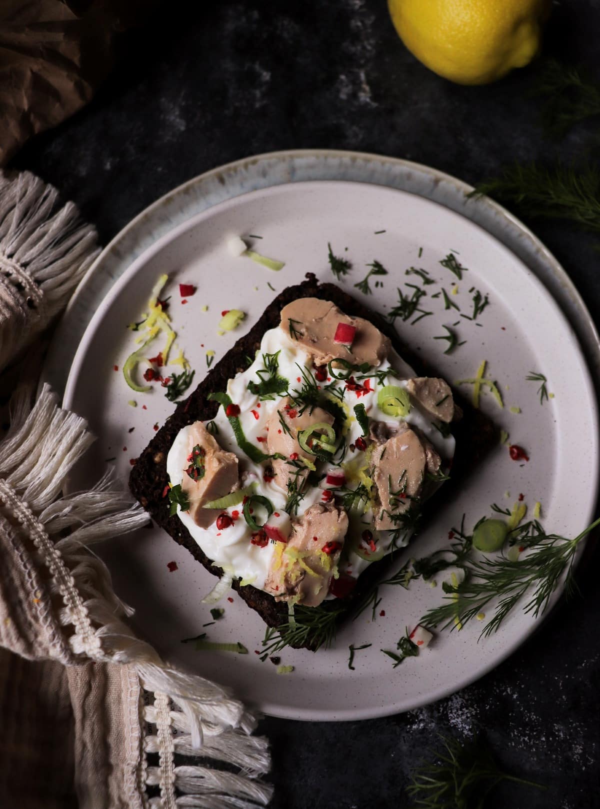 Open-faced cod liver toast on rye with fresh herbs
