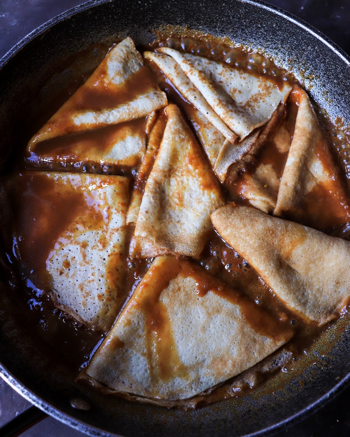 Crêpes Suzette-style crepes simmering in orange rum dulce de leche caramel sauce.