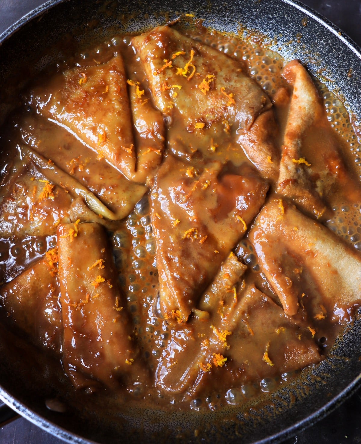 Folded Crêpes cooking in bubbling dulce de leche dark rum sauce.