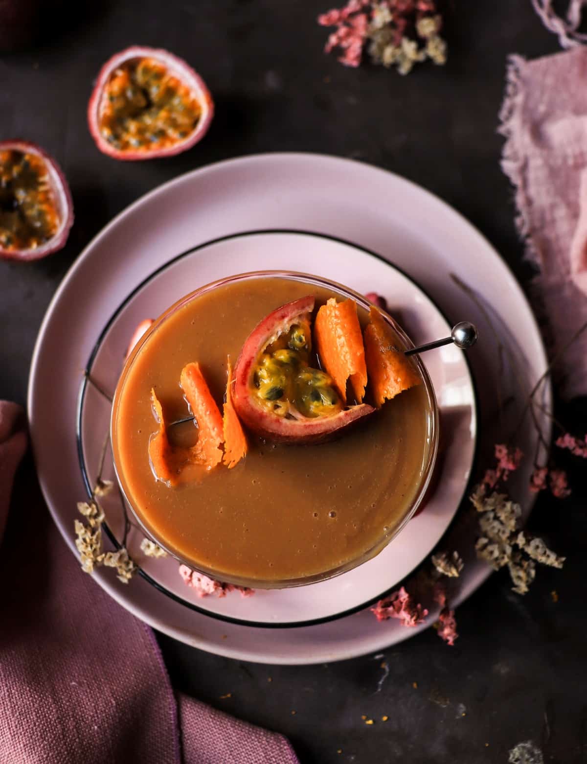 Passion fruit cocktail with dulce de leche, orange peel, and tropical fruit garnish.