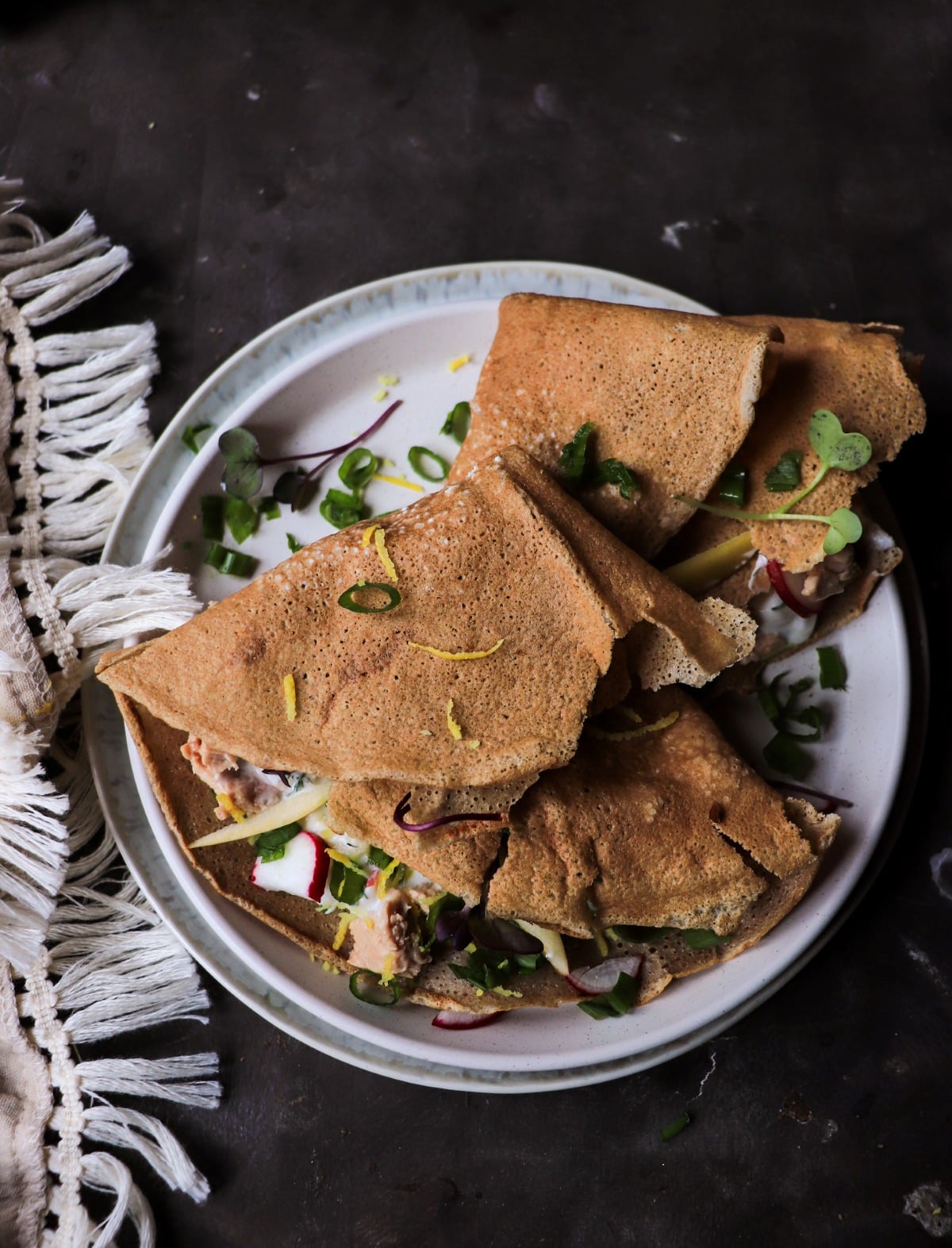 Scandinavian-inspired  rye crêpes with smoked cod liver, apple, lemon zest, and herbs