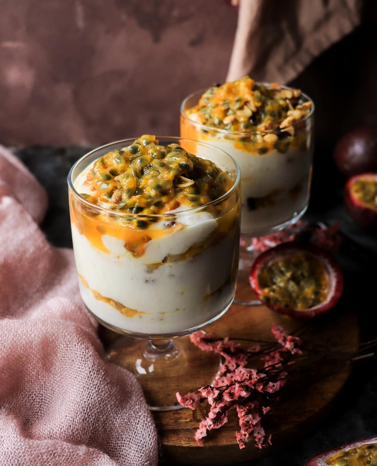Tropical yogurt parfait with banana, passion fruit, and granola in individual glasses