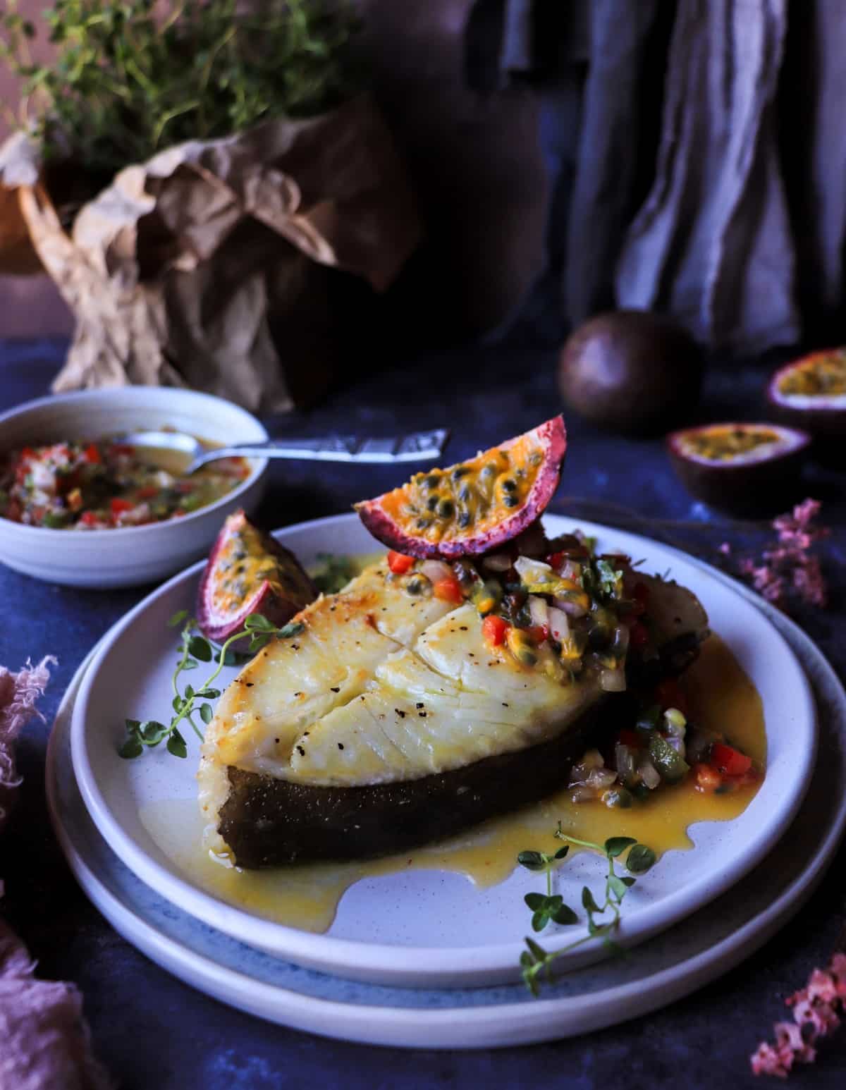 One-pan halibut with passion fruit salsa served with fresh passion fruit and thyme.