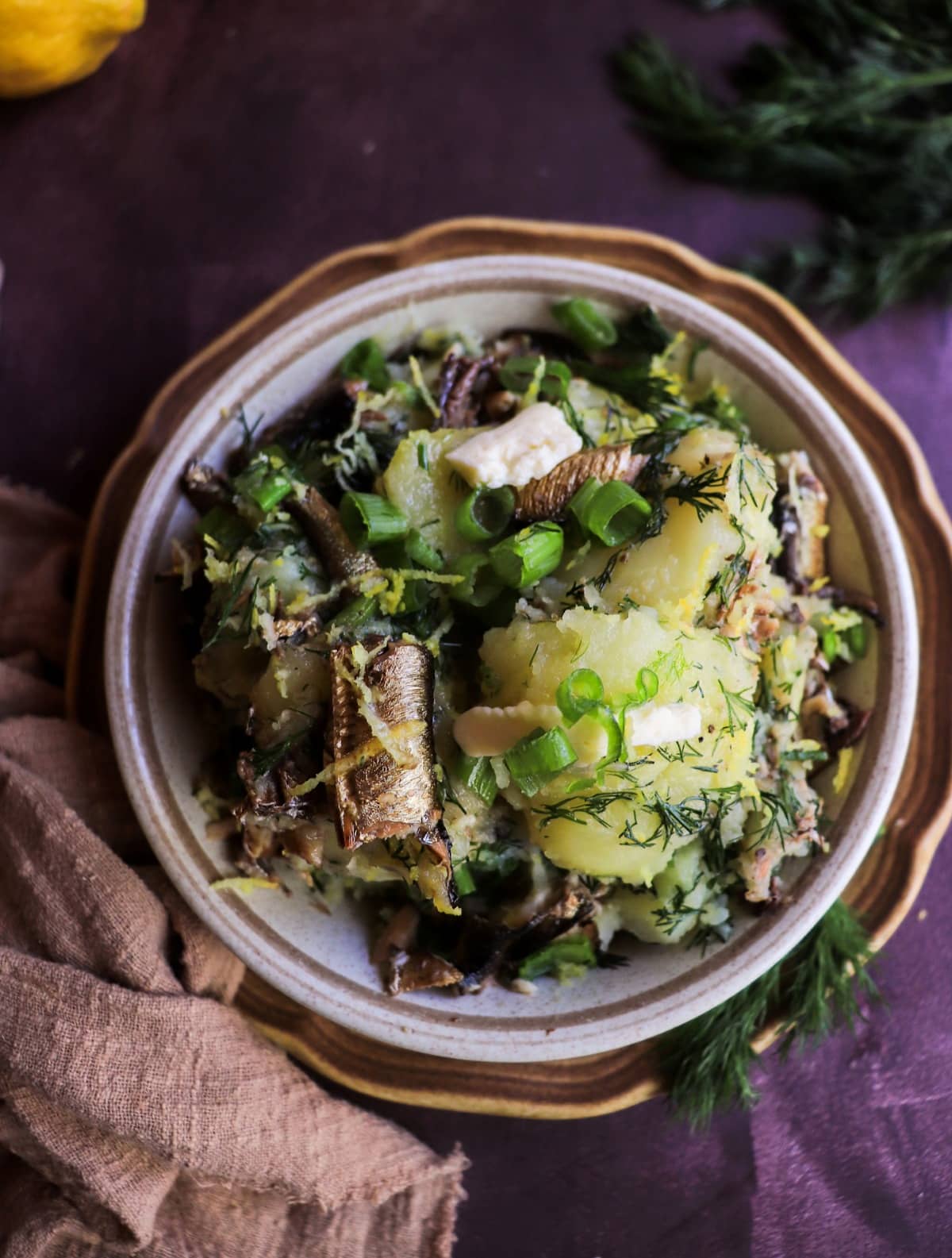 Rustic potato dish with smoked sprats, lemon zest, dill, and green onions.