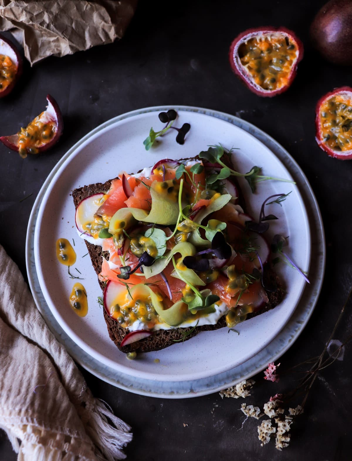 Rye toast with smoked salmon, dill cream, and passion fruit. A unique Nordic-inspired appetizer with a tropical twist.