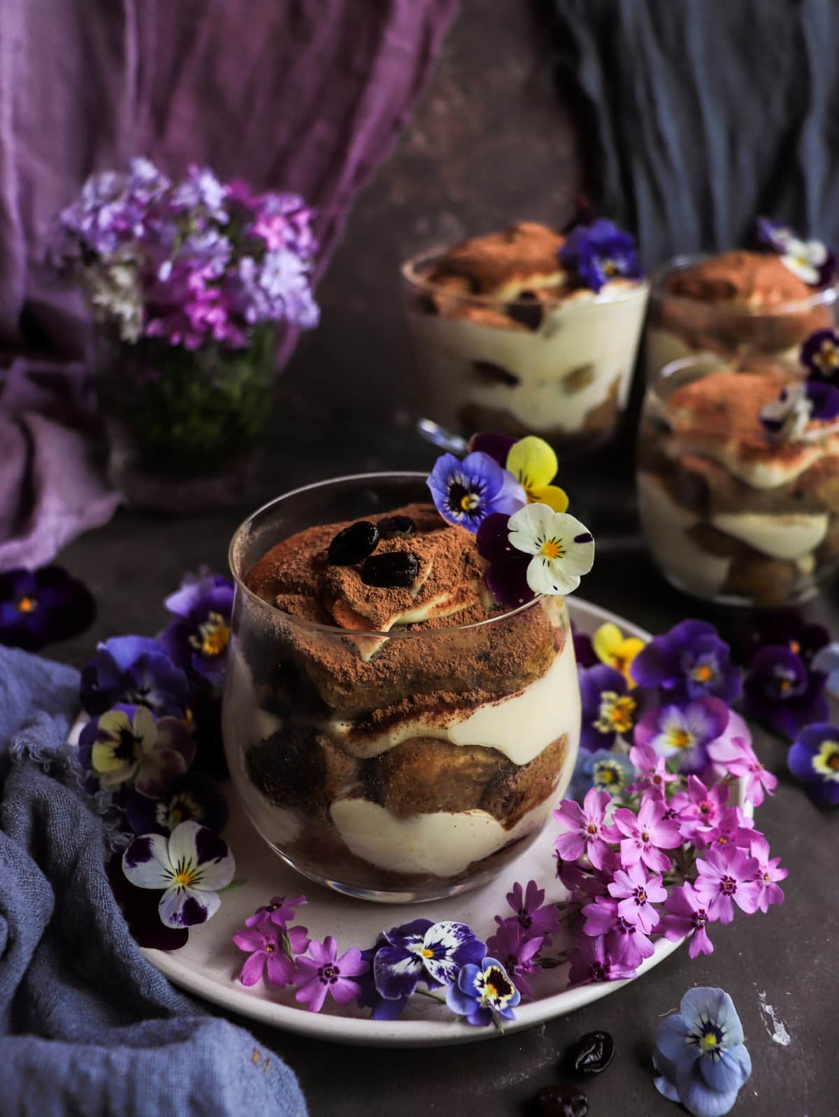 individual violet tiramisu desserts with mascarpone cream, coffee-soaked ladyfingers and cocoa powder.