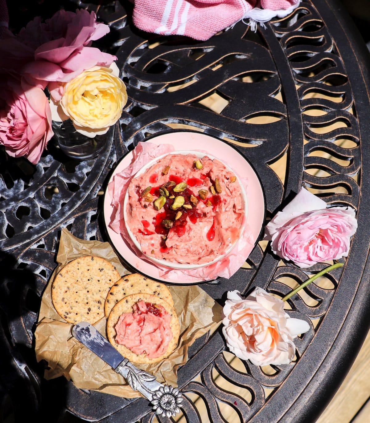 Rose compound butter with rose petal jam and crackers on an outdoor table
