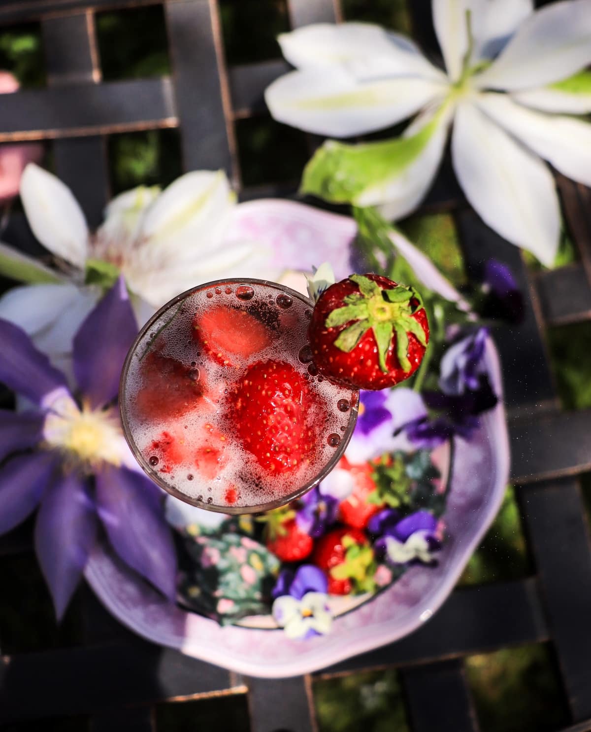 Floral French 75 cocktail with strawberries and violet liqueur