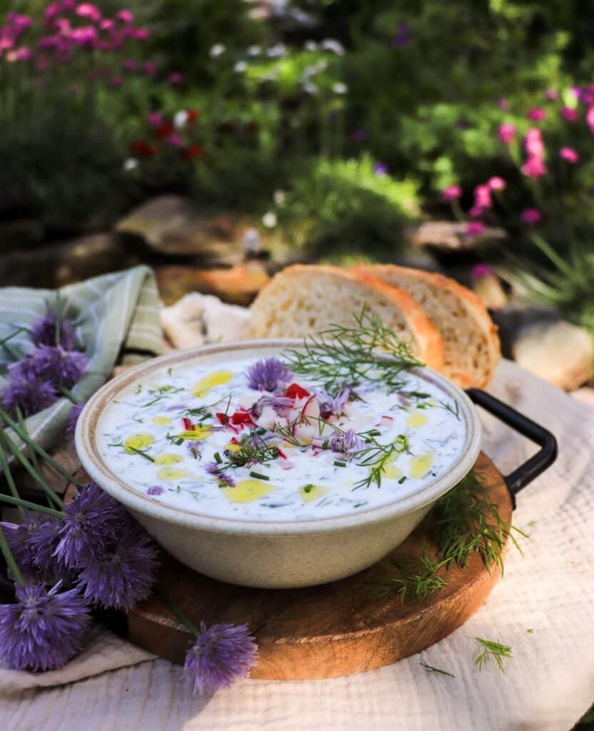Cold cucumber soup with kefir and yogurt topped with radishes, dill, and chives
