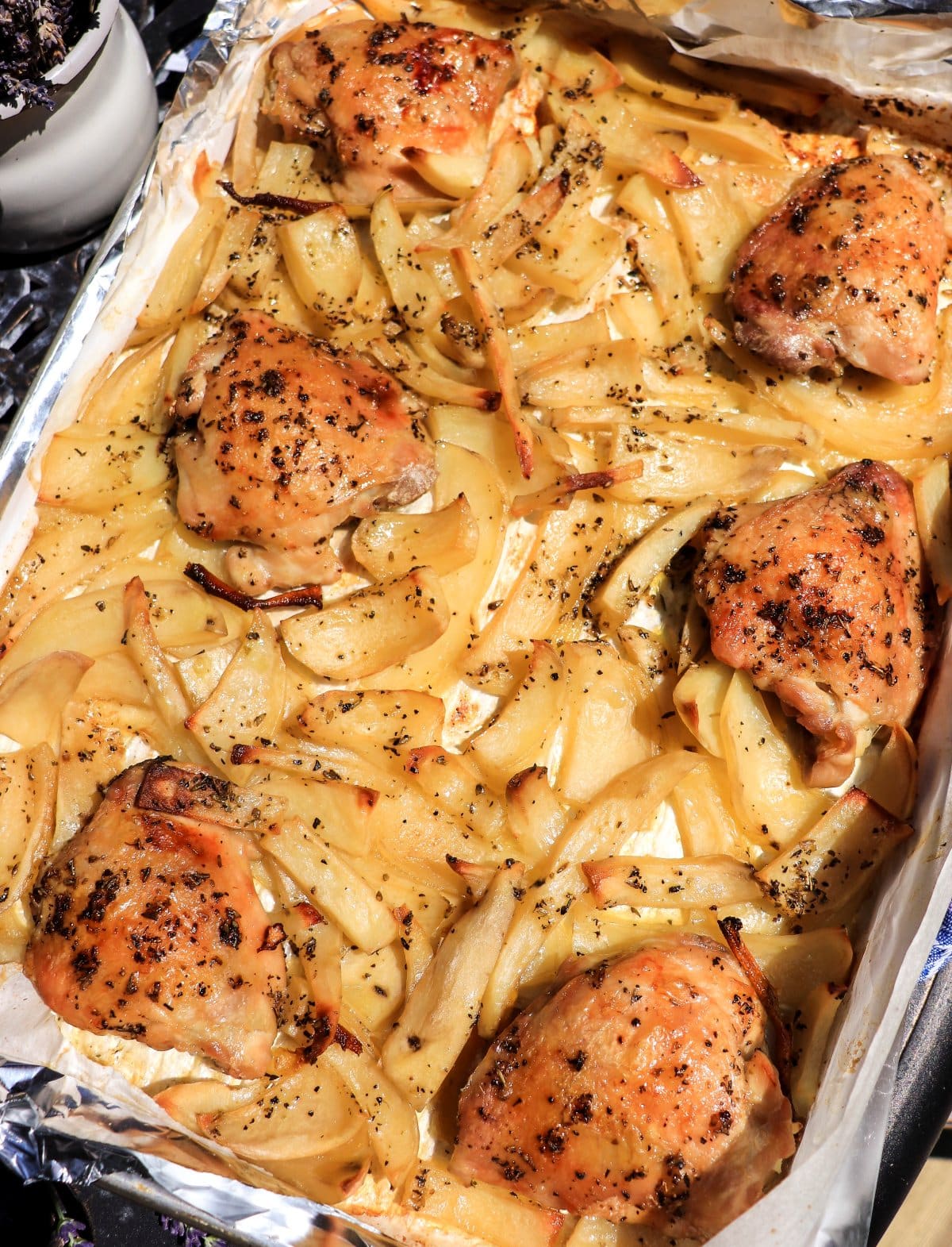Roasted chicken thighs and potatoes with lavender on a baking sheet